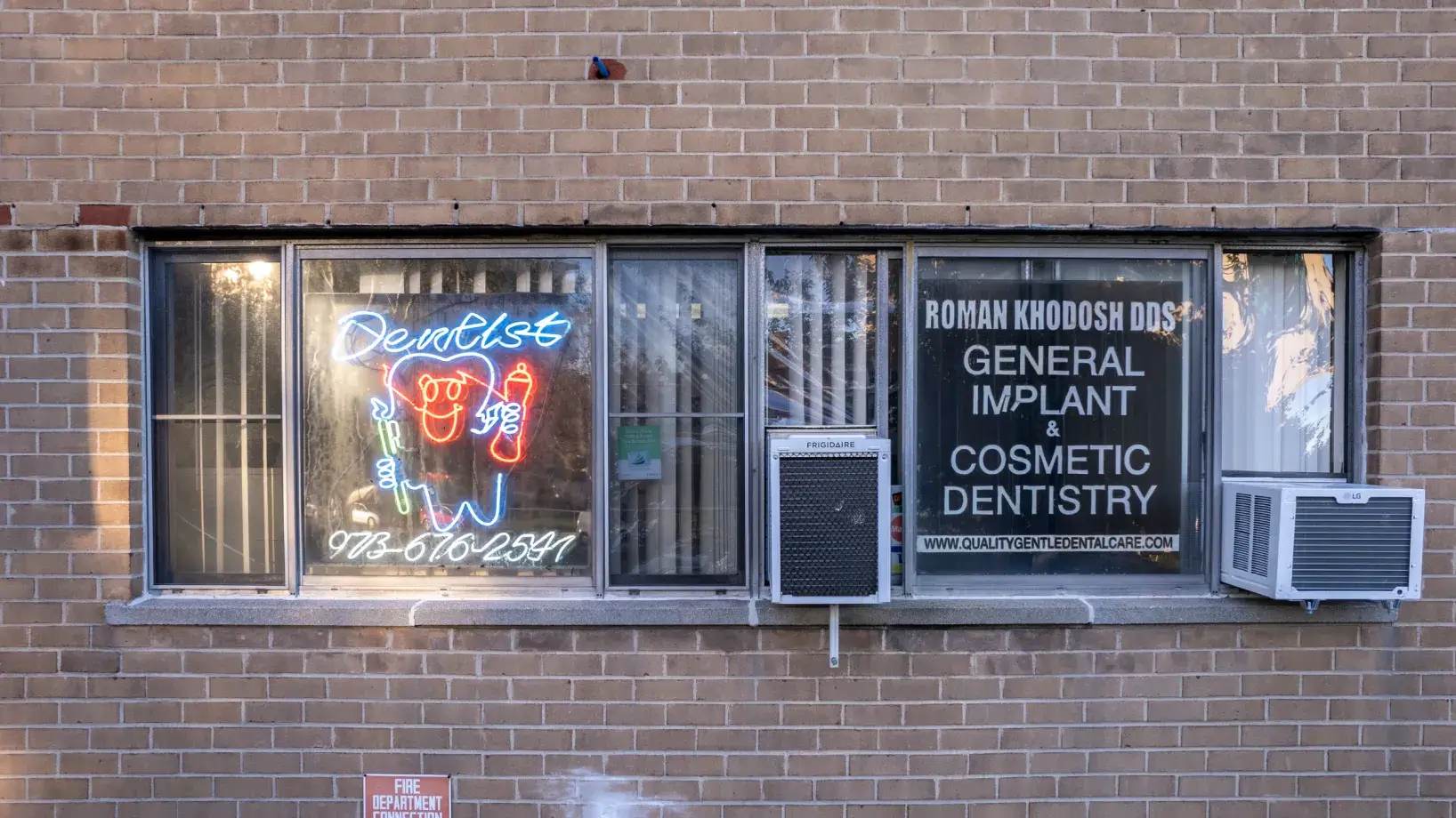 a brick building with a neon sign in the window